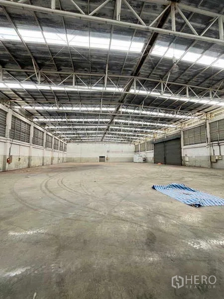 货栈 出租在Lat Krabang, Bangkok - 高挑仓库内部，钢结构桁架与大型卷闸门。