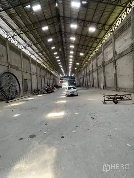 Warehouse for rent in Phra Samut Chedi, Samut Prakan - Spacious high-ceiling warehouse interior with skylights and central aisle.