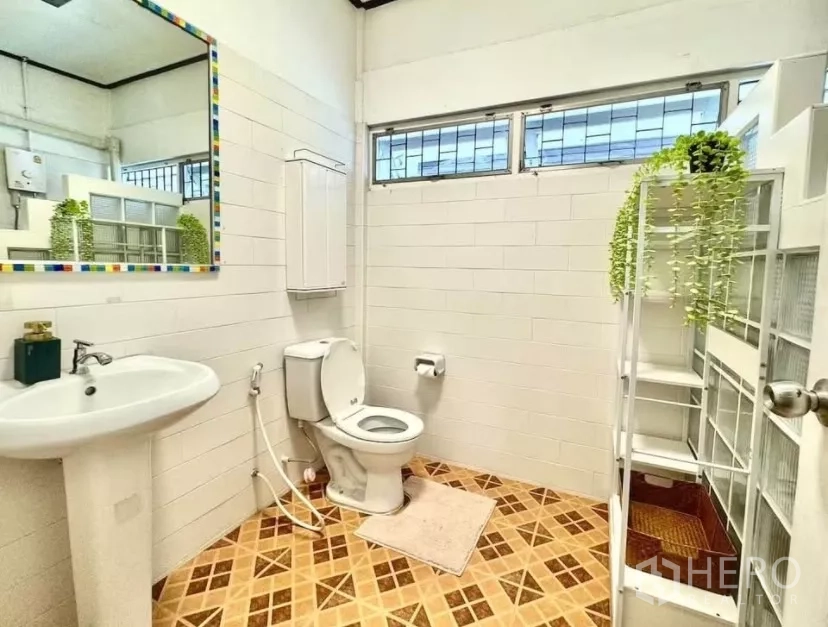 Townhouse for rent in Watthana, Bangkok - White-tiled bathroom with pedestal sink, toilet, window and shelving.