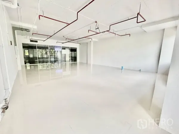 Office Space for rent in Khlong Toei, Bangkok - White-boxed office interior with polished floors, ceiling conduits and sprinklers, and a glass-partitioned entry suitable for reception or meeting room.