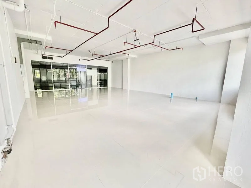 Office Space for rent in Khlong Toei, Bangkok - White-boxed office interior with polished floors, ceiling conduits and sprinklers, and a glass-partitioned entry suitable for reception or meeting room.