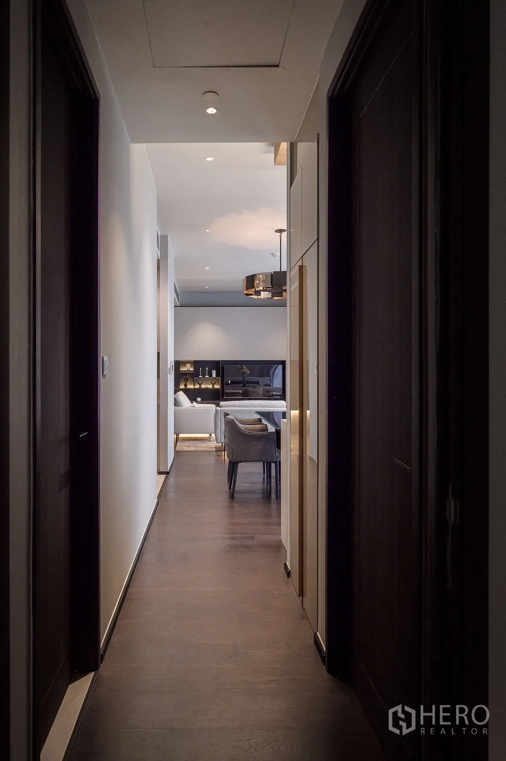 Condominium for rent or sale in Watthana, Bangkok - Long hallway with recessed lights and dark wood floors opening to the living–dining area.