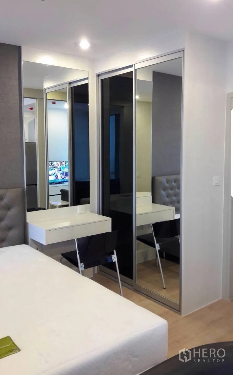Condominium for rent in Bang Rak, Bangkok - Bright studio bedroom with tufted headboard, mirrored wardrobe and built-in vanity.