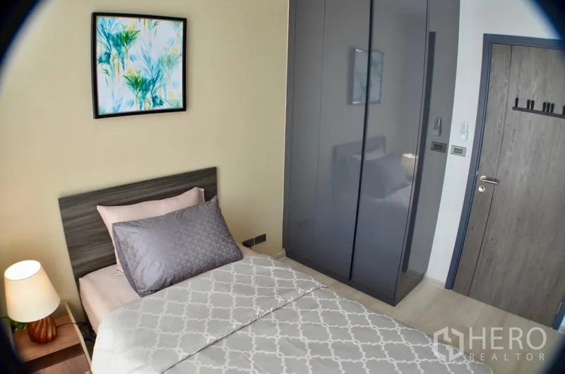 คอนโด ให้เช่าในWatthana, Bangkok - มุมเตียงเดี่ยวพร้อมตู้เสื้อผ้าบานเงาและภาพแขวนผนัง