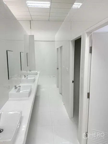 โรงงาน ให้เช่าในPathum Thani - ทางเดินห้องน้ำรวมสะอาด พร้อมอ่างล้างหน้าและห้องสุขาหลายห้อง