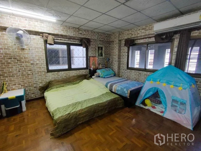 Townhouse for sale in Bang Phlat, Bangkok - Spacious bedroom with parquet flooring, multiple windows, air conditioner and a kids play tent.