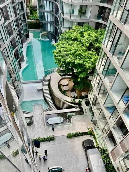 Condominium for rent - Aerial view of the condominium courtyard featuring a curving swimming pool, large tree and terraced walkways.