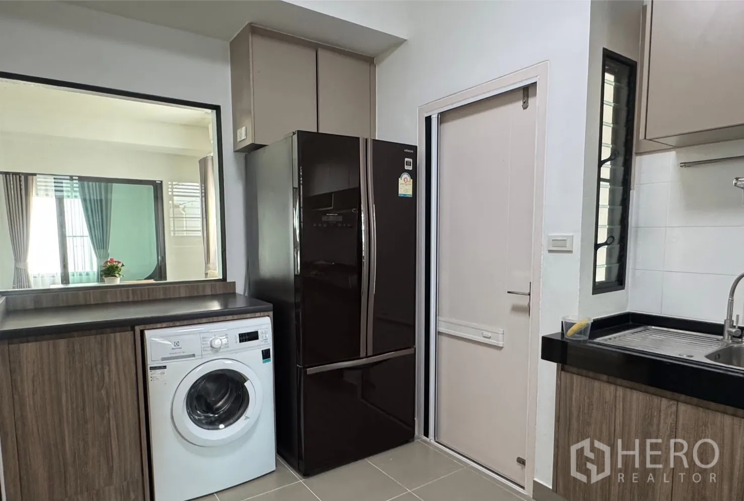 บ้าน for rent in Bang Phli, Samut Prakan - ครัวสมัยใหม่พร้อมเครื่องซักผ้า ตู้เย็นบานคู่สีดำ และอ่างล้างจานสเตนเลสข้างหน้าต่าง