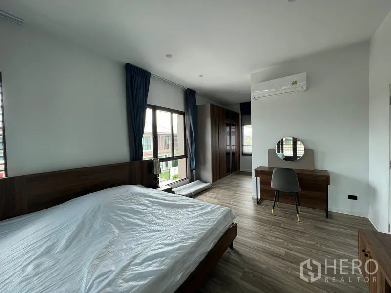 Detached House for rent in Bang Kapi, Bangkok - Master bedroom angle showing desk, wardrobe cabinetry and wall-mounted air conditioner.