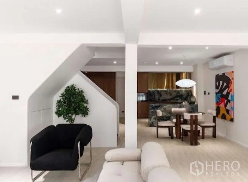 Townhouse for sale in Sathon, Bangkok - Open plan area with staircase, dining set and indoor plant near the kitchen.