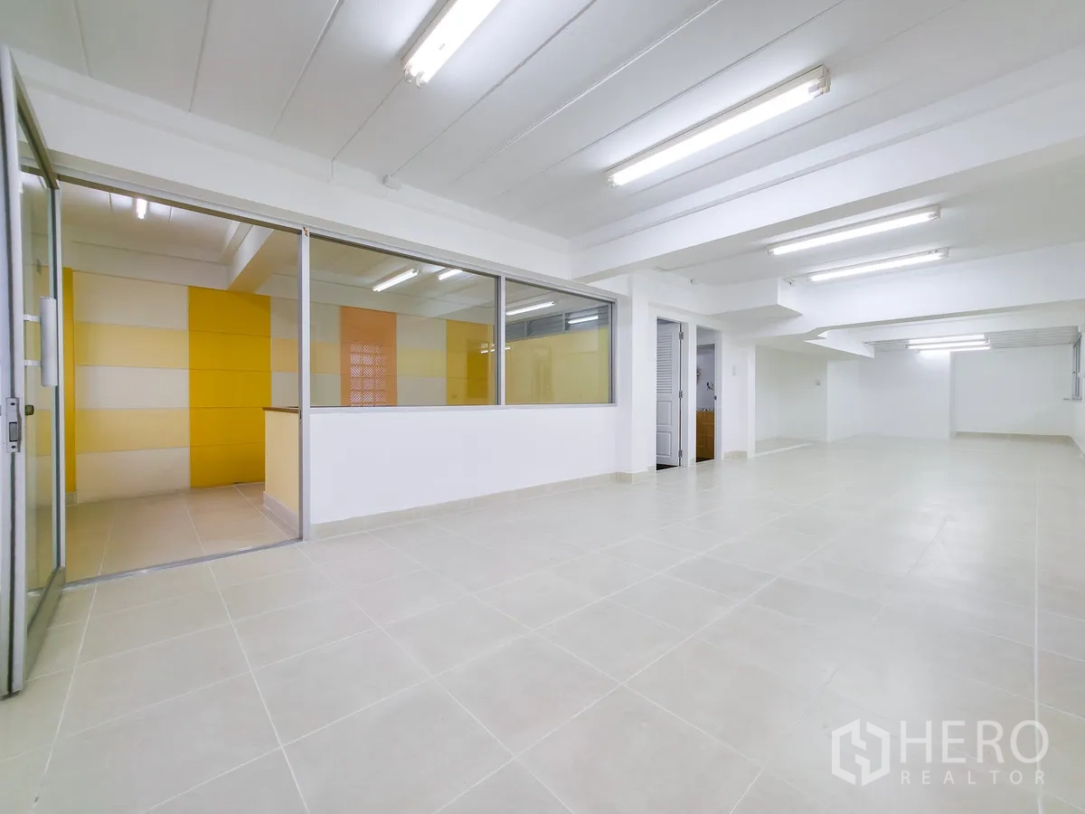 办公室 for rent in Khlong Toei, Bangkok - 开放式空间，旁侧为黄墙玻璃隔断的会议室。