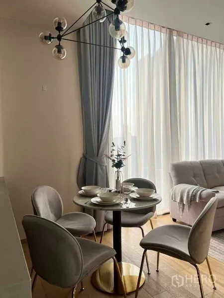 Condominium for rent - Cozy dining nook with a round table set for four beneath a modern chandelier beside sheer draped windows.