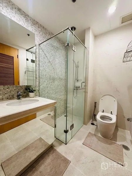 公寓 出租在Bang Rak, Bangkok - 客厅另一视角，展示沙发、电视柜与通往阳台的大玻璃。