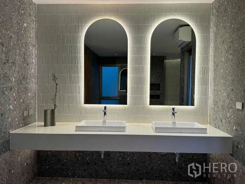 Home Office for sale in Chatuchak, Bangkok - Vanity zone with twin sinks and backlit arched mirrors on a textured feature wall.