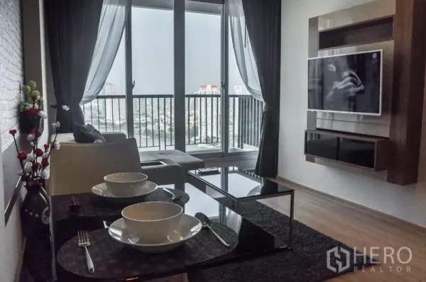 Condominium for rent in Sathon, Bangkok - Modern living room with sofa, dining set, wall‑mounted TV and balcony city view in a Sathon condo.