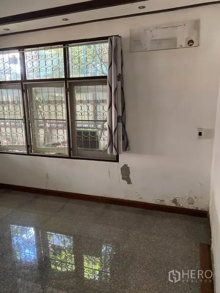 联排别墅 出租在Lat Phrao, Bangkok - 采光角落，大窗配金属防护栏，墙面有待翻新