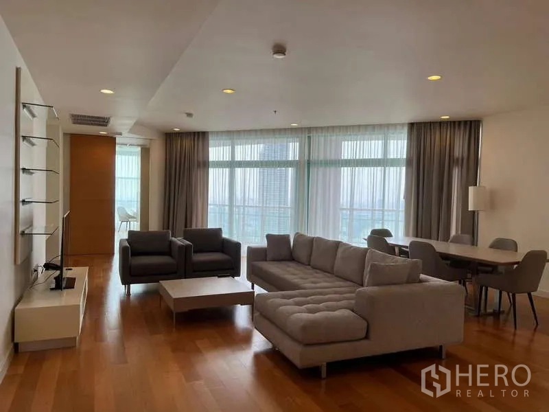 Condominium for rent in Bang Kho Laem, Bangkok - Spacious living room with L-shaped sofa, armchairs, dining table, and floor-to-ceiling windows.