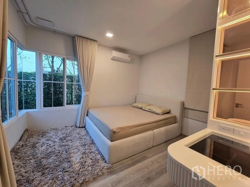 独立式住宅 出租在Bang Phli, Samut Prakan - 一层卧室，转角落地窗、长绒地毯与内置展示柜。