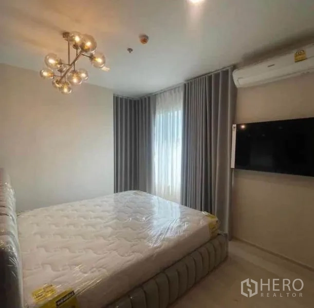Condominium for rent or sale - Bedroom with mattress, draped window, wall-mounted TV and air conditioning.