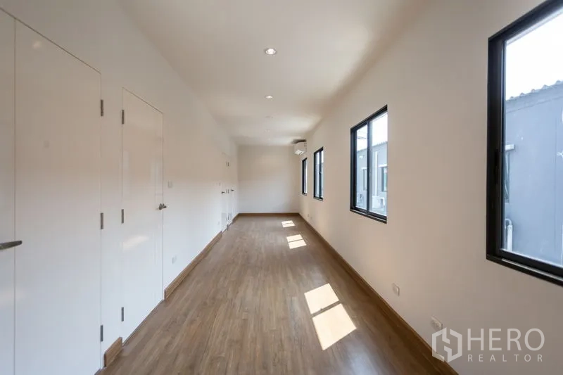 ทาวน์เฮาส์ ให้เช่าในBang Phli, Samut Prakan - โถงชั้นบนสว่าง พื้นลามิเนตลายไม้ ผนังสีขาวและหน้าต่างกรอบอลูมิเนียมดำ