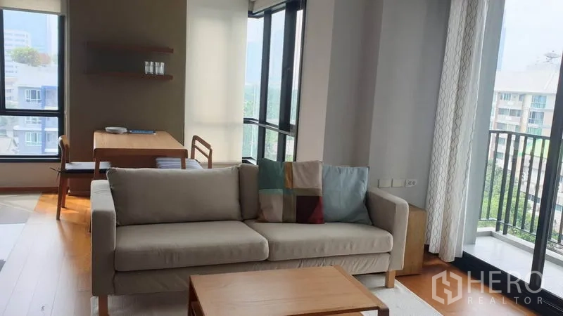 คอนโด ให้เช่าในPhaya Thai, Bangkok - มุมห้องนั่งเล่นติดระเบียง โซฟาสีเบจ หน้าต่างสูงจากพื้นจดเพดาน วิวเขตพญาไท