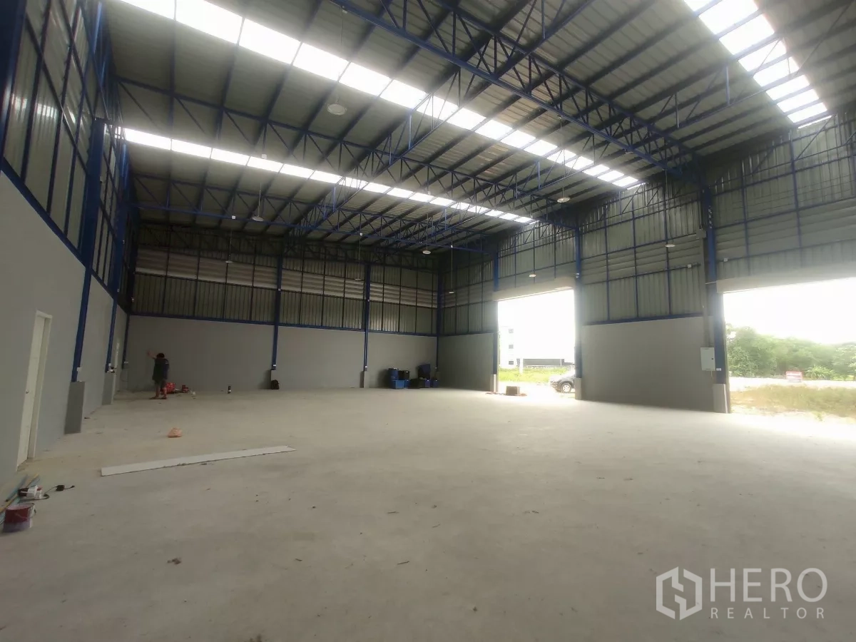工厂 出售在Khlong Toei, Bangkok - 开阔的厂房混凝土地面，天窗屋顶与双卷闸通向室外。