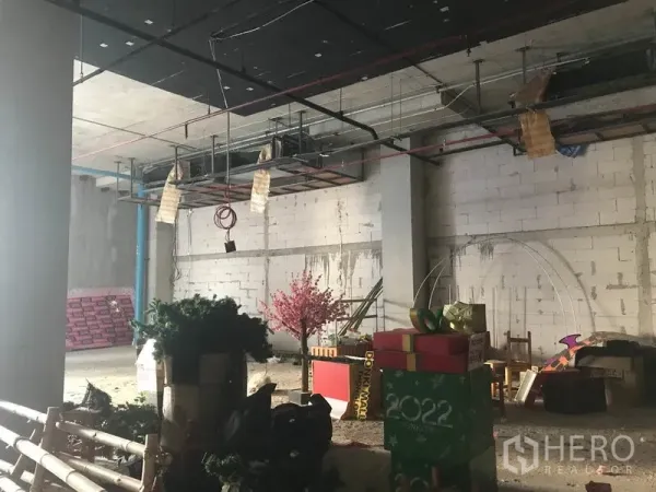Retail Space for rent in Khlong Toei, Bangkok - Wide view of an unfinished shop space with suspended piping, concrete pillars and stored decor.