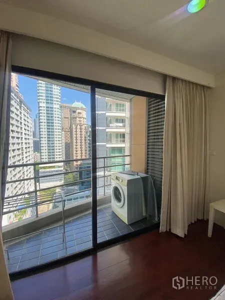Condominium for rent in Pathum Wan, Bangkok - Sliding glass door to balcony with washing machine and city view.