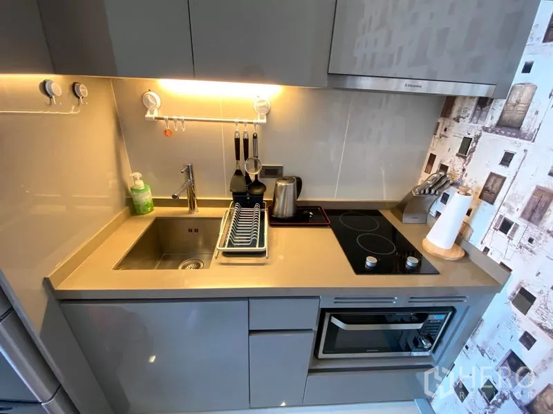 Condominium for rent in Bang Rak, Bangkok - Close-up of kitchenette featuring induction hob, sink, oven, and under-cabinet lighting.