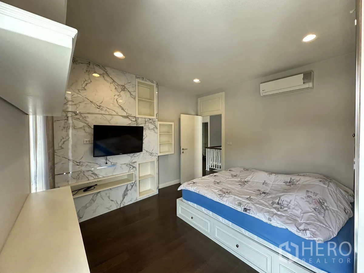 บ้าน ให้เช่าหรือขายในLam Luk Ka, Pathum Thani - ห้องนอนผนังลายหินอ่อน ทีวีติดผนัง และชั้นวางของ