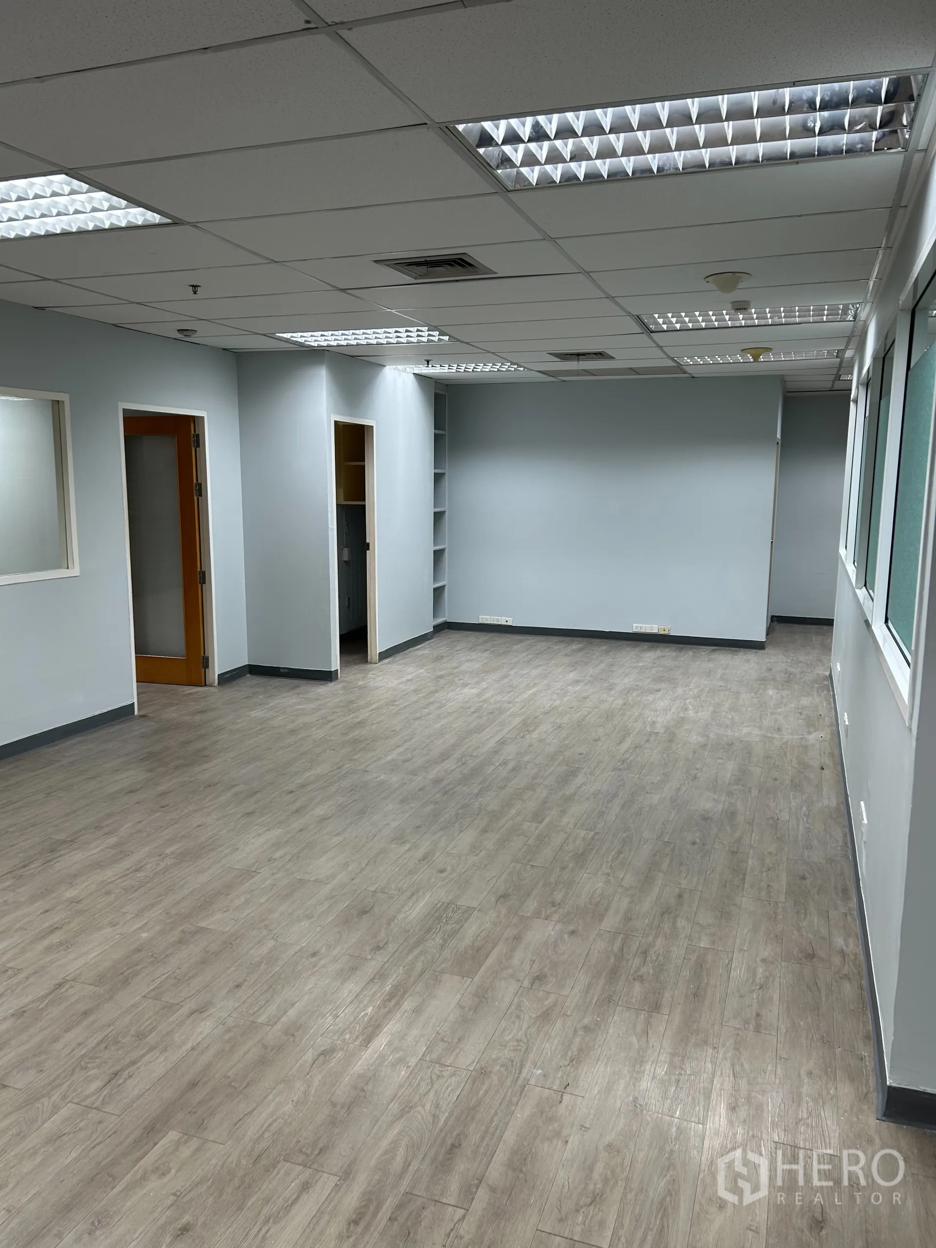 办公空间 出租在Khlong Toei, Bangkok - 拉长的开放式办公区全景，木纹地板与中性色隔断。