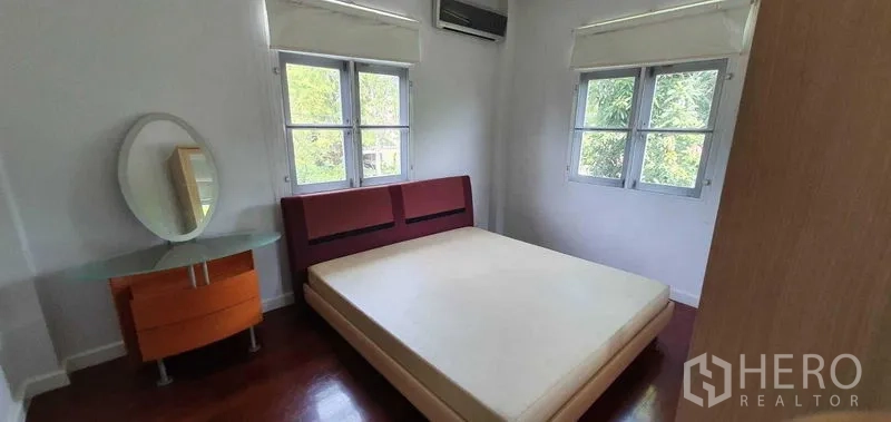 Detached House for rent in Prawet, Bangkok - Guest bedroom with upholstered headboard, bedside tables and corner windows.