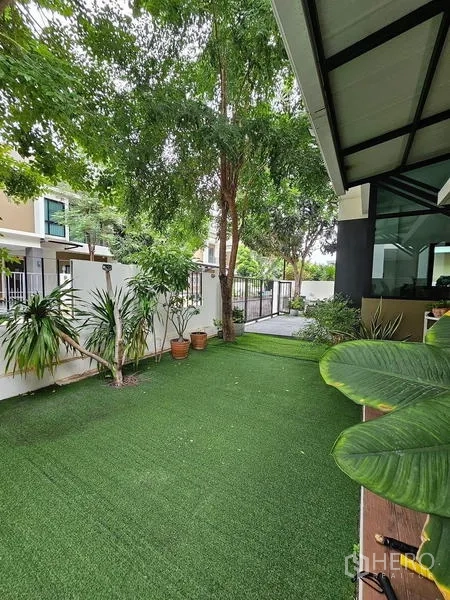 Detached House for rent in Bang Phli, Samut Prakan - Landscaped side garden with artificial turf, trees and potted plants.