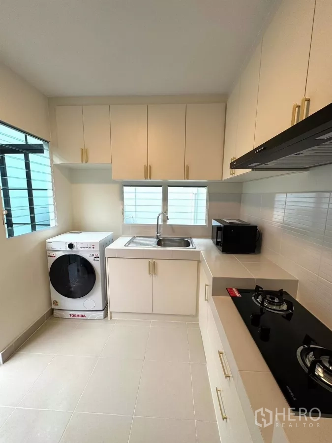Detached House for rent in Bang Phli, Samut Prakan - Modern kitchen with gas hob, upper cabinets, microwave and washer.