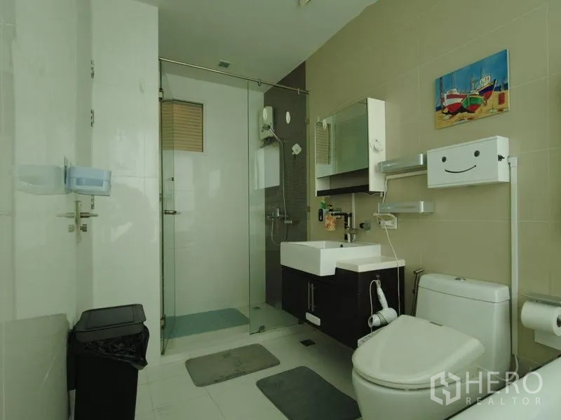 Condominium for rent in Watthana, Bangkok - Modern bathroom with glass-enclosed shower, vanity and toilet.