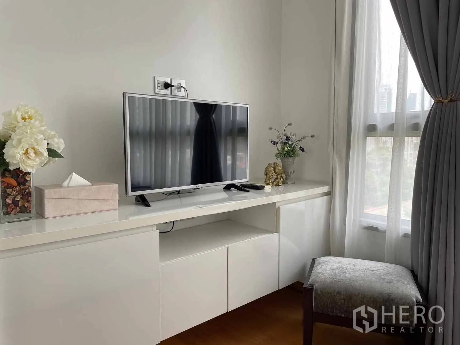公寓 for rent in Watthana, Bangkok - 白色内置电视柜与平面电视，旁有半透窗帘的窗户。