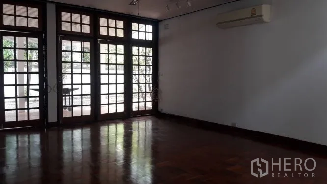 บ้าน ให้เช่าในYan Nawa, Bangkok - ห้องนั่งเล่นกว้าง พื้นไม้ปาร์เกต์ และประตูกระจกบานเฟรนช์สูงเชื่อมสู่ชานบ้าน