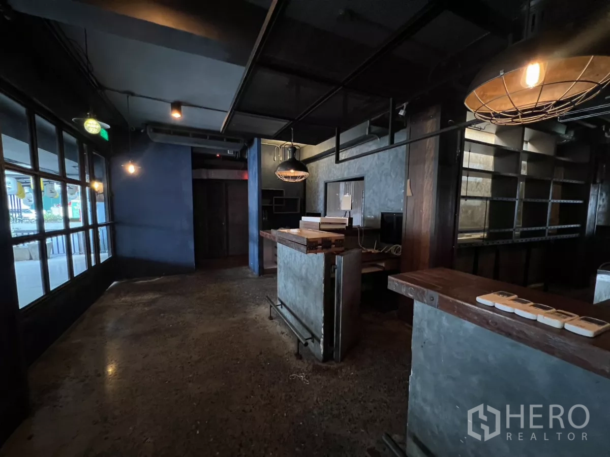 零售空间 出租 - 接待区配粗犷吧台、货架与工业吊灯。