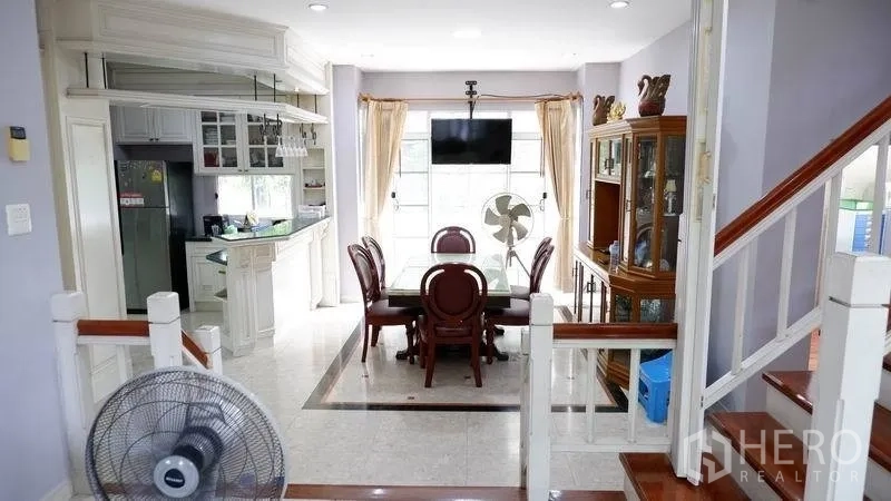 Detached House for rent in Prawet, Bangkok - View from the stairs toward the dining room and kitchen with built-in display cabinet and tiled flooring.