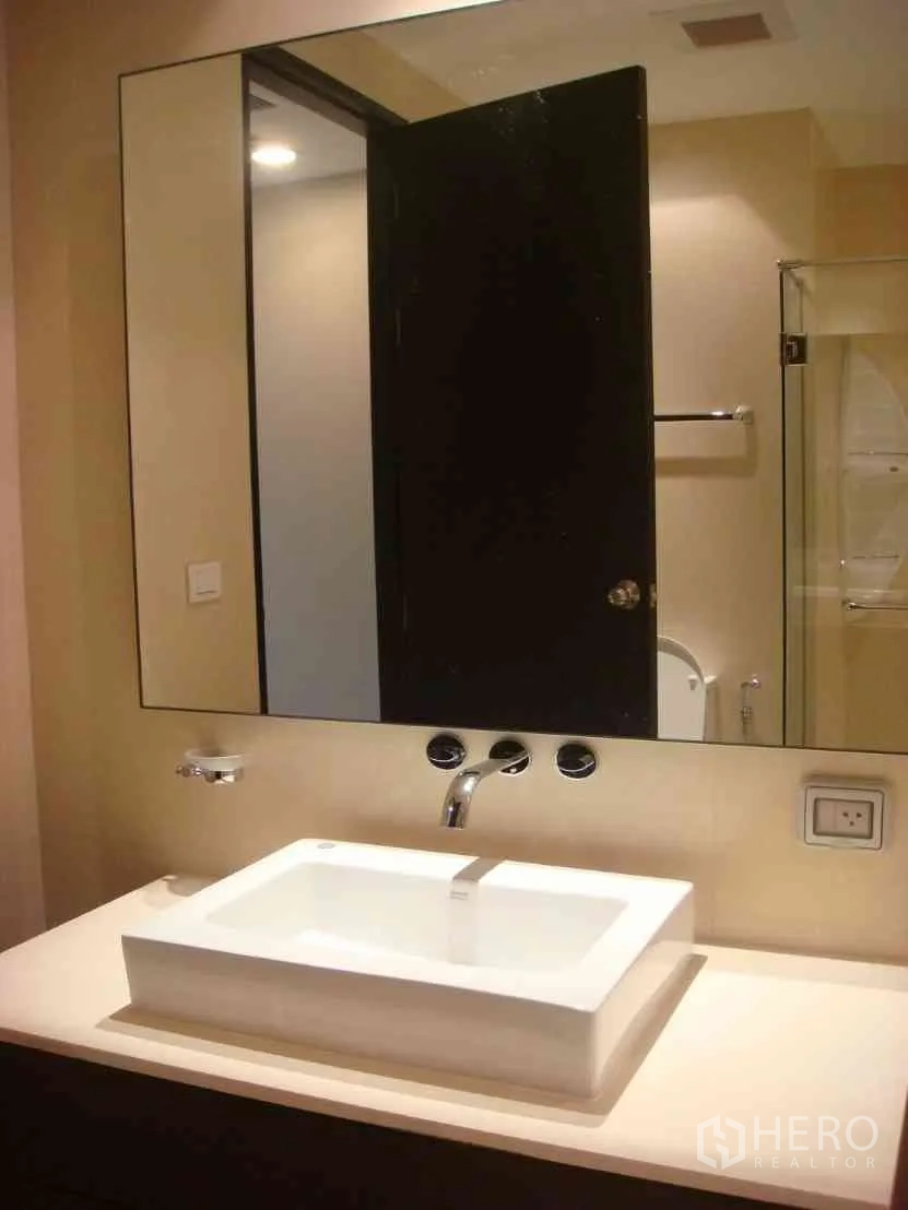 Condominium for rent in Watthana, Bangkok - Modern bathroom featuring a large mirror and rectangular vessel sink on a light countertop.