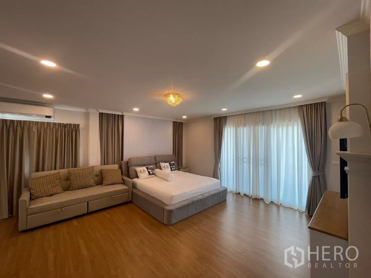 独立式住宅 出租在Bang Phli, Samut Prakan - 主卧配落地窗与纱帘，临阳台休憩区。