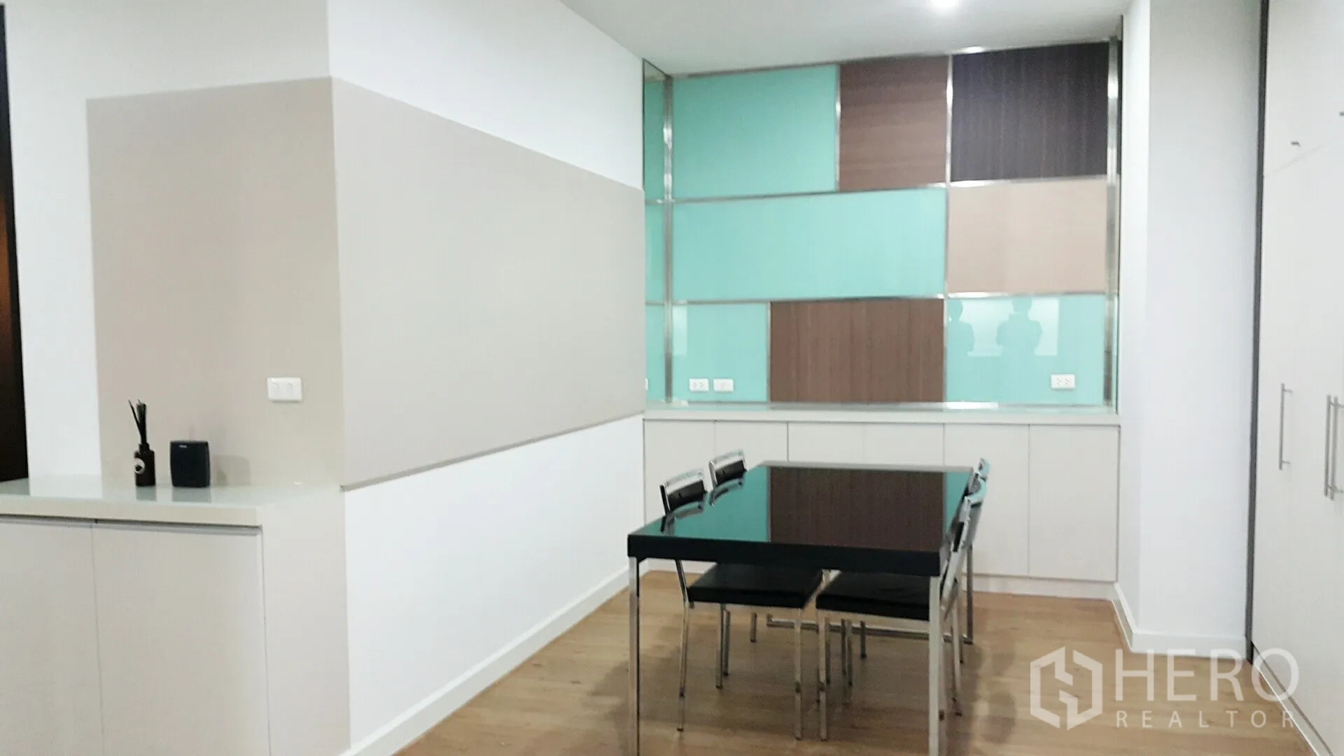 คอนโด ให้เช่าในKhlong Toei, Bangkok - มุมรับประทานอาหารสว่าง โต๊ะกระจก พื้นไม้ ตู้บิลท์อิน และผนังตกแต่งสีสันในคอนโดทันสมัย