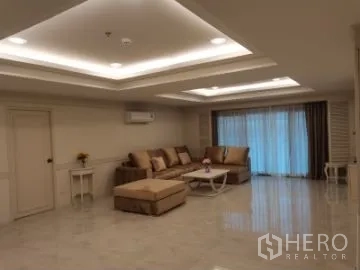 อพาร์ทเมนท์ ให้เช่าในWatthana, Bangkok - ห้องนั่งเล่นกว้างพร้อมไฟฝ้าหลุม โซฟาสีเบจ พื้นเงา และประตูบานเลื่อนติดผ้าม่าน