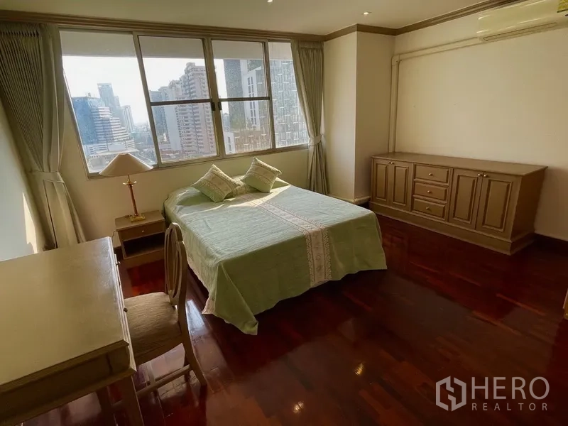 Condominium for rent or sale in Watthana, Bangkok - Bedroom with large window and skyline views, wooden floors, and built-in storage.