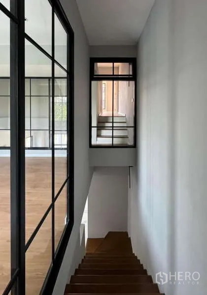 联排别墅 出租或出售在Prawet, Bangkok - 木楼梯与黑框玻璃隔断的走廊