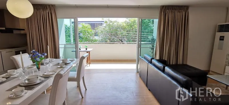 อพาร์ทเมนท์ ให้เช่าในKhlong Toei, Bangkok - พื้นที่นั่งเล่นและทานอาหารเปิดออกสู่ระเบียง มองเห็นต้นไม้ผ่านประตูกระจกเลื่อน