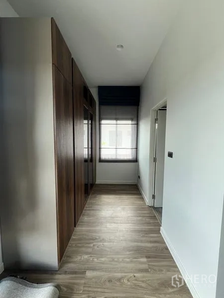 Detached House for rent in Bang Kapi, Bangkok - Hallway with built-in wardrobes and wood flooring leading toward the bathroom.