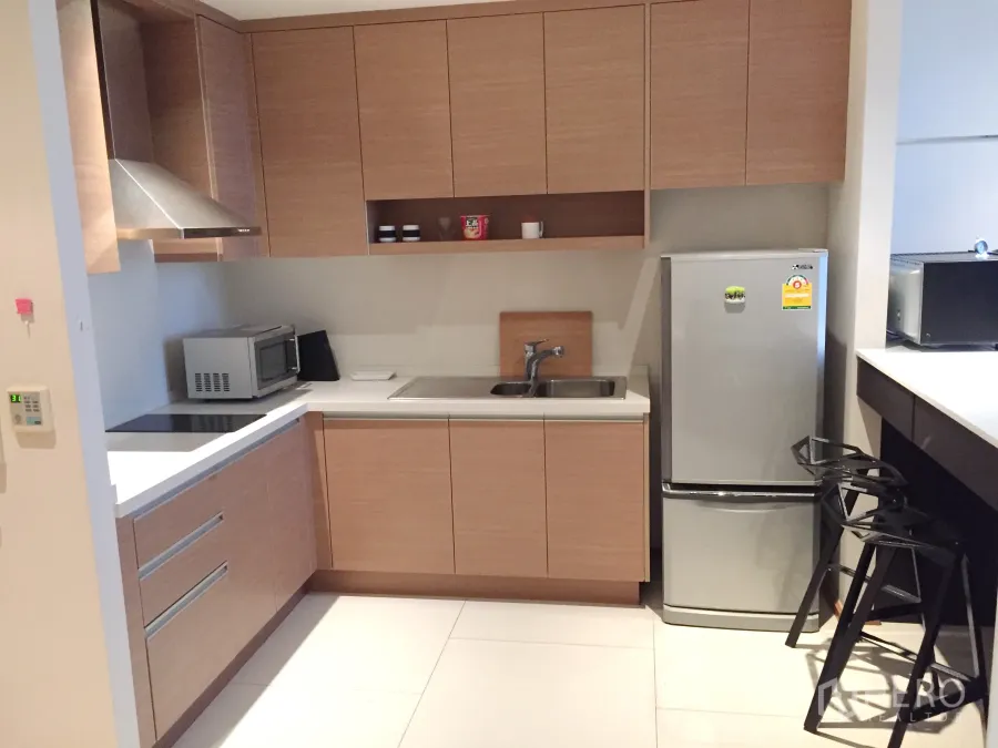 คอนโด ให้เช่าในKhlong Toei, Bangkok - ครัวรูปตัวแอลตู้ไม้ เตาไฟฟ้า เครื่องดูดควัน ไมโครเวฟ และตู้เย็นภายในคอนโด