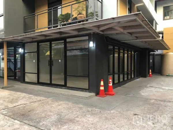 办公空间 出租在Phaya Thai, Bangkok - 一层转角单位，黑色框架玻璃立面与遮雨棚。