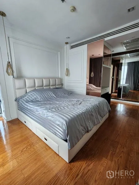 公寓 出租在Bang Rak, Bangkok - 主卧配软包床头、吊灯、镜面衣柜与木地板。